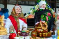 Two women are at table with pancakes and painted utensils during Shrovetide festivities