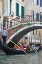 Gondola boat with passengers passing under a bridge in Venice, Italy