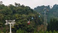 Gondola lifts moving over mountain from post to post with green trees in the area of Sun Moon Lake Ropeway in Yuchi Township.