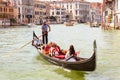 Gondola with people sails on Grand Canal in sunny Venice