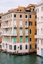 A gondola with tourists is sailing along the Grand Canal amid the facades of Venetian houses standing on the water in Royalty Free Stock Photo