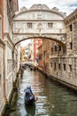 Gondola with tourists sails on old canal under medieval Bridge of Sighs, Venice, Italy Royalty Free Stock Photo