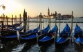 Gondolas anchored at pier of San Marco square at sunrise on Grand Canal towards San Giorgio Maggiore, Venice, Italy. Royalty Free Stock Photo