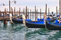 Gondolas moored on wooden dock by Saint Mark square with San Giorgio Maggiore church and island with cloudy blue sky in background Royalty Free Stock Photo