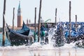 Waves splashing between parked gondolas in the Venetian lagoon