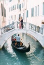 Gondole in chanel of Venice, Italy. Lovers hugging and kissing stand on the bridge of the canal