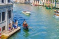 Gondolier and tourists on gondola traditional boat sailing on water of Grand Canal in Venice