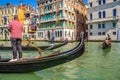 Gondolier and tourists on gondola traditional boat sailing on water of Grand Canal in Venice