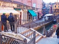 Gondoliers dressed for cold weather wait for passengers on a bridge over a Venetian canal Royalty Free Stock Photo