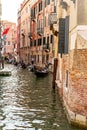 Gondoliers and tourists along narrow canal in Venice Italy