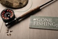 Fly fishing reel, rod, and flies on a light wood background