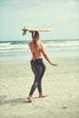 Gone surfing. a beautiful young woman going for a surf at the beach.