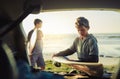 Gone surfing. two young brothers unloading their surfboards from the back of a car by the beach.