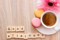 Good afternoon message coffee break concept  white cup of frothy espresso coffee with colourful French macaroons on wooden Royalty Free Stock Photo