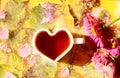 Good autumn morning wishes: a cup of tea in the shape of a heart among pastel flowers and water drops on a yellow background, a Royalty Free Stock Photo