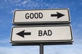 White two street signs with arrow on metal pole with word good and bad