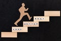 Good - Better - Best paper man climbing the steps to success in a conceptual image over black background Royalty Free Stock Photo