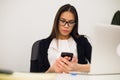 Good business talk. Cheerful young beautiful woman in glasses talking on mobile phone and using laptop with smile while Royalty Free Stock Photo