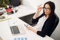 Good business talk. Cheerful young beautiful woman in glasses talking on mobile phone and using laptop with smile while Royalty Free Stock Photo