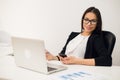 Good business talk. Cheerful young beautiful woman in glasses talking on mobile phone and using laptop with smile while Royalty Free Stock Photo