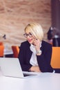 Good business talk. Cheerful young beautiful woman in glasses talking on mobile phone and using laptop Royalty Free Stock Photo