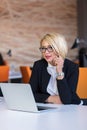 Good business talk. Cheerful young beautiful woman in glasses talking on mobile phone and using laptop Royalty Free Stock Photo