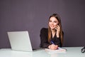 Good business talk. Cheerful young beautiful woman in glasses talking on mobile phone and using laptop with smile while sitting at Royalty Free Stock Photo