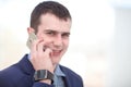 Good business talk. Handsome young man in formalwear talking on the phone and smiling while sitting at the office desk Royalty Free Stock Photo