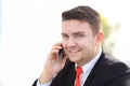 Good business talk. Handsome young man in formalwear talking on the phone and smiling while sitting Royalty Free Stock Photo