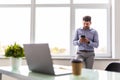 Good business talk. Handsome young man use phone and using computer while working in the office Royalty Free Stock Photo