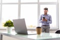 Good business talk. Handsome young man use phone and using computer while working in the office Royalty Free Stock Photo