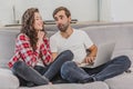 A good couple while shopping online using a laptop and smiling while sitting at a couch at home. A woman asks her Royalty Free Stock Photo