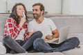 A good couple while shopping online using a laptop and smiling while sitting at a couch at home. Royalty Free Stock Photo