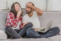 A good couple while shopping online using a laptop and smiling while sitting at a couch at home. Royalty Free Stock Photo