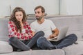 A good couple while shopping online using a laptop and smiling while sitting at a couch at home. A woman was offended by Royalty Free Stock Photo