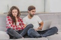 A good couple while shopping online using a laptop and smiling while sitting at a couch at home. A woman was offended by Royalty Free Stock Photo