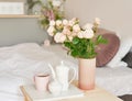 Good cozy morning. Bouquet of rose flowers in vase on table. Hotel room with bed. Check in hotel. Rest and relaxation. Coffee in