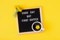 Good day but first coffee. Motivational quote on letter board, bouquet yellow flowers and cup of coffee on yellow background. Royalty Free Stock Photo