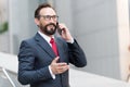 A good deal! Bearded businessman speaks by phone and laughs.View of handsome attractive businessman in glasses using smartphone