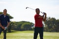 Good follow throughs make all the difference. two handsome men playing a game of golf.