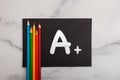 Good grade A plus letter on black canvas with coloring pencils