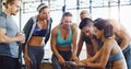 Good health is always trending. a group of happy young women using a digital tablet together in a gym.