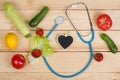 Good healthy and diet concept - Blackboard in shape of heart, stethoscope and vegetables, fruits and berries Royalty Free Stock Photo