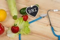 diet concept - Blackboard in shape of heart with text BMI Body mass index, stethoscope, vegetables, fruits and berries Royalty Free Stock Photo