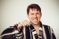 Good-humored man in bathrobe brushing teeth, toned