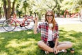 Good-humoured young woman sitting on the grass with sincere smile. Outdoor photo of blithesome cauc