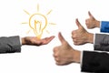 Good idea concept. Hand holding a lightbulb while other hands showing thumbs up hand sign. Businessman idea concept Royalty Free Stock Photo