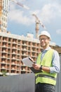 Good job. Young happy civil engineer or construction supervisor wearing helmet looking away and smiling while inspecting