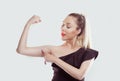 Good, look, my muscles are growing. Young happy woman flexing muscles showing her strength isolated white light blue wall