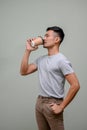 Good looking Asian man sipping coffee, holding takeaway coffee cup, hand in pocket